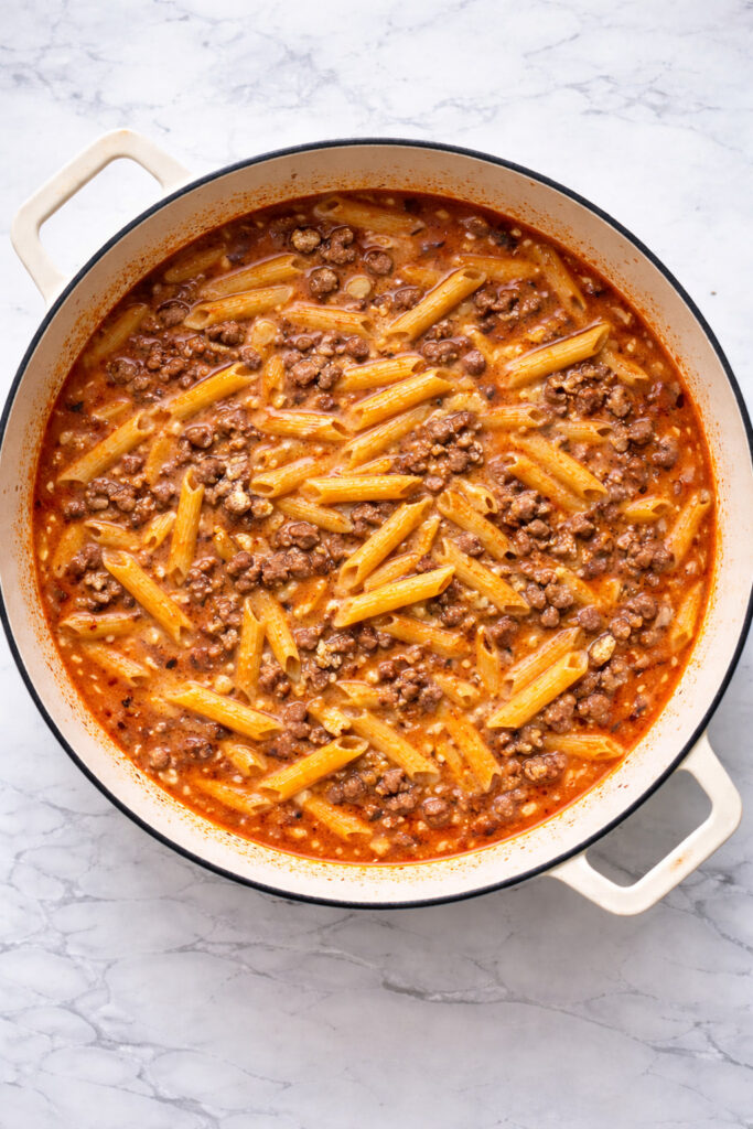 Tomato sauce and penne pasta added to beef pasta
